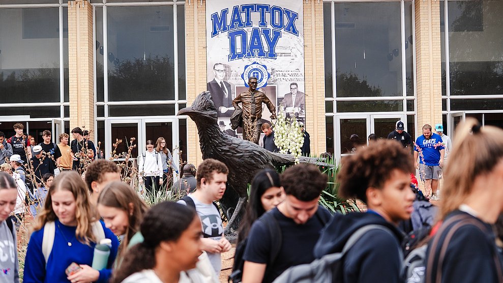 Photograph of LCU students in front of a large bronze statue of a Chaparral and the statue of F.W. Mattox in the background, in front of a banner with the words "Mattox Day"