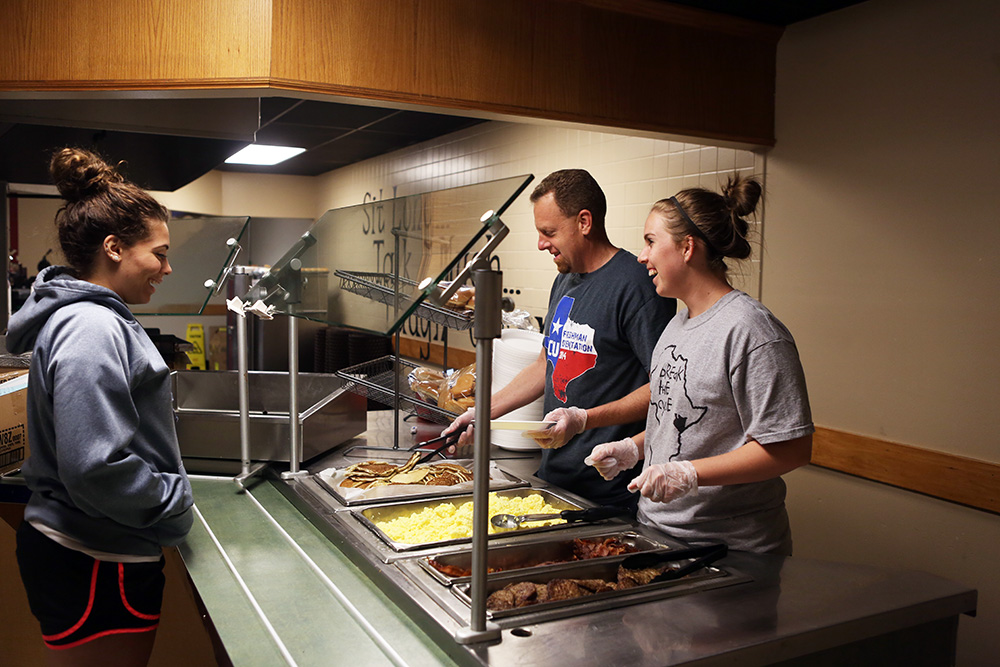 Staff serving pancakes to students